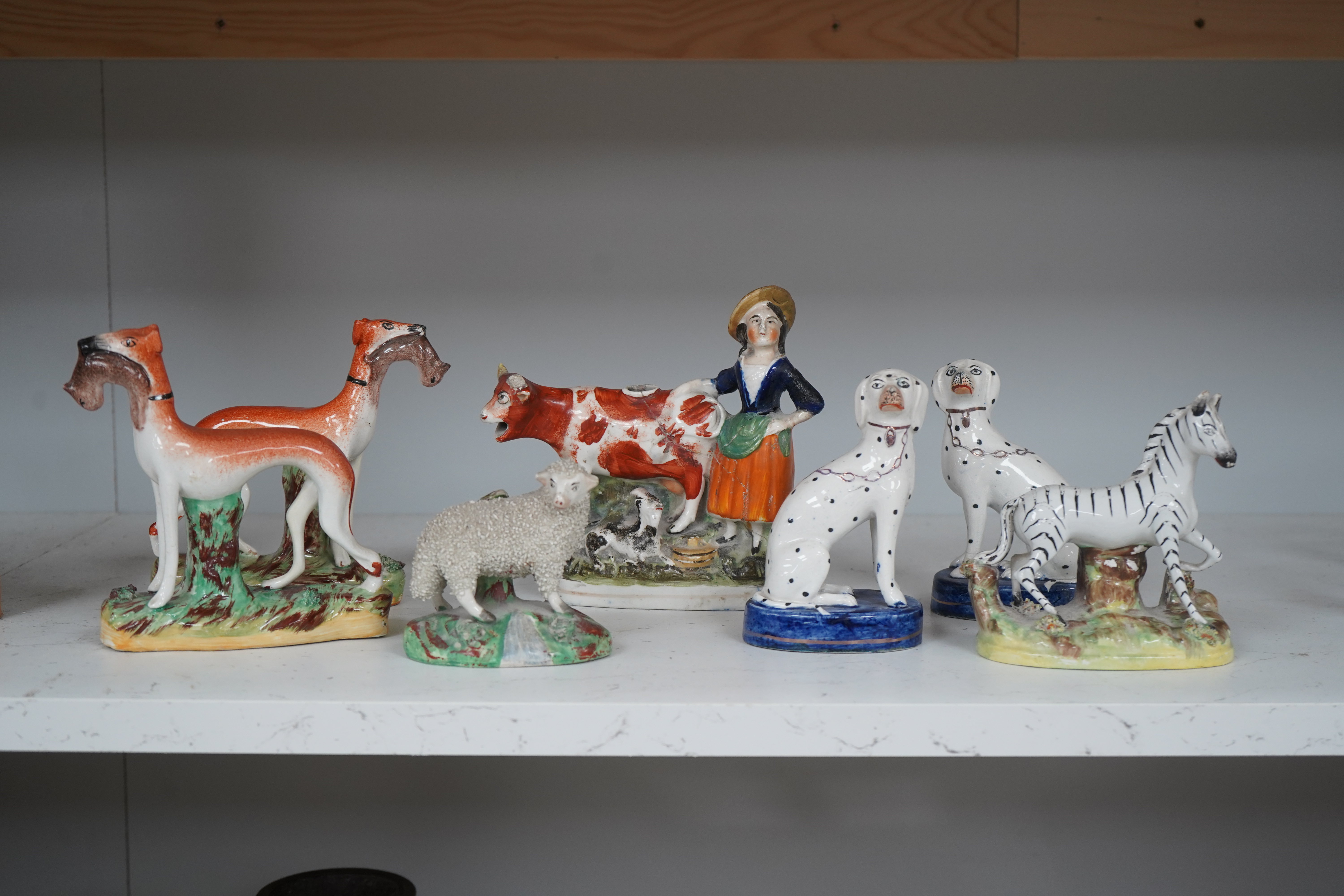 Eight Staffordshire figures to include a pair of Dalmatian’s and a cow creamer figure, largest 18cm wide. Condition - varies, poor to good